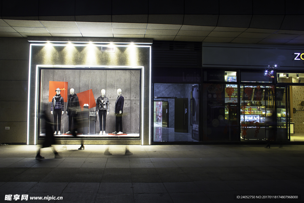 夜晚衣服店橱窗前逛街的行人