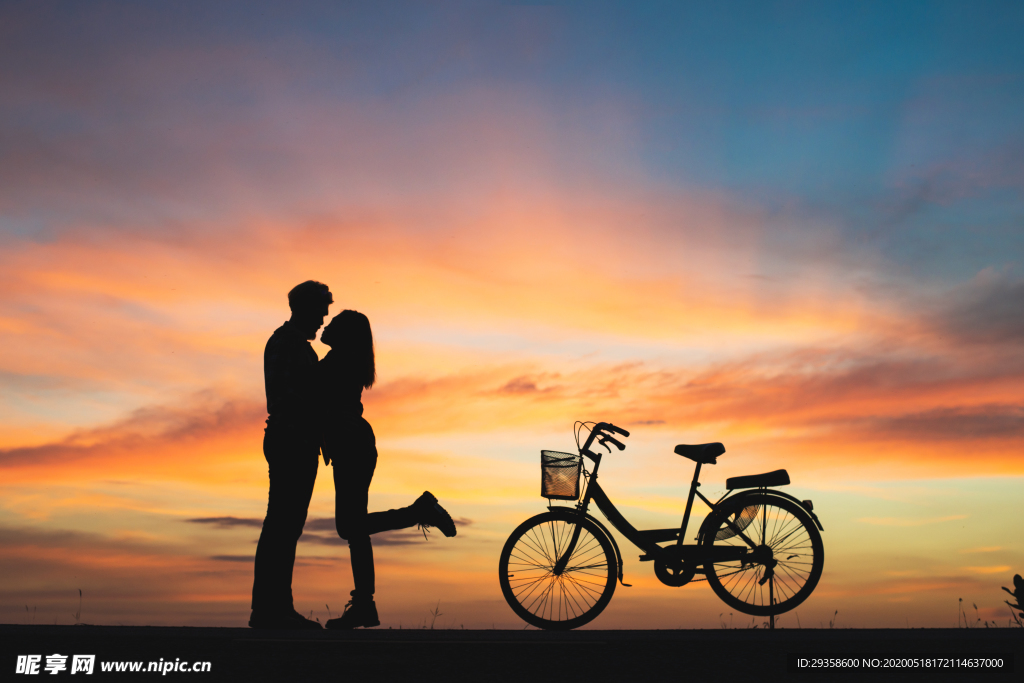 情侣与自行车在夕阳下的剪影