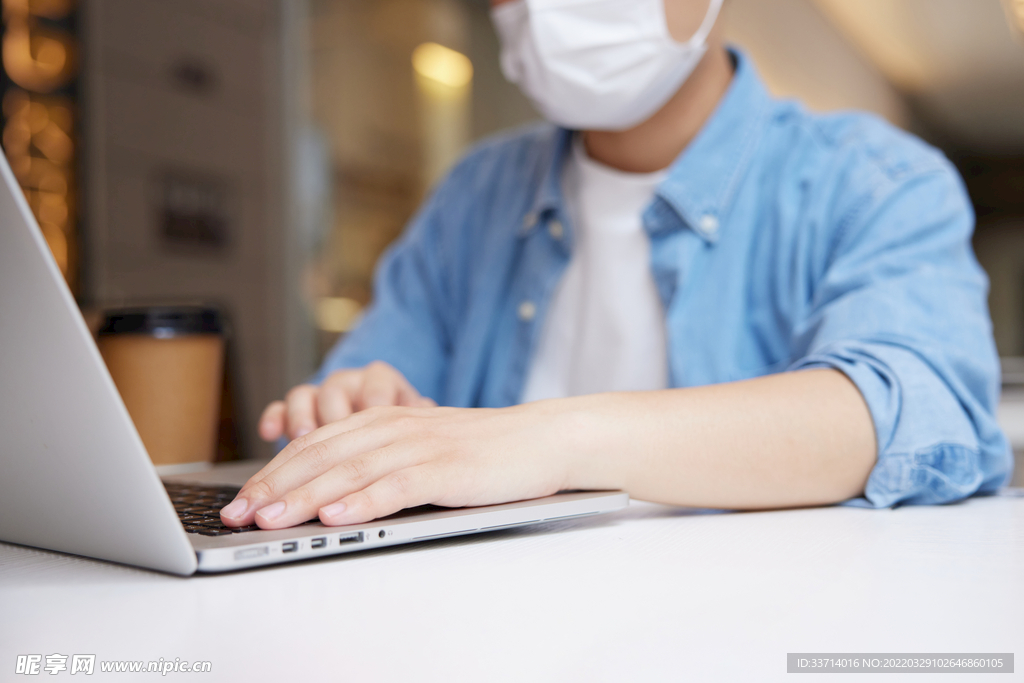 室内戴口罩使用笔记本电脑的人