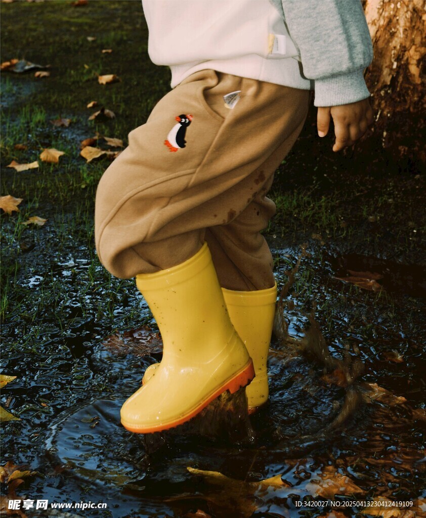 小孩穿黄雨靴踩积水