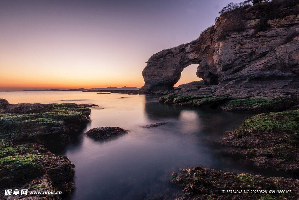 海边日落时的天然石拱门