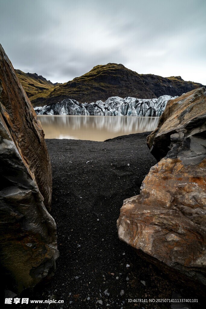 黑沙滩上的岩石与远方瀑布
