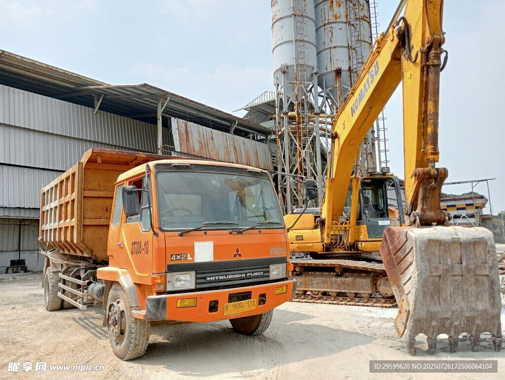 工地旁的橙色自卸车与挖掘机