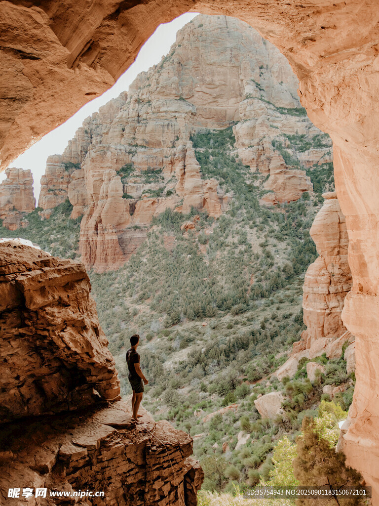 人立于山间岩洞眺望美景