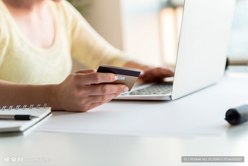 女性手持信用卡使用笔记本