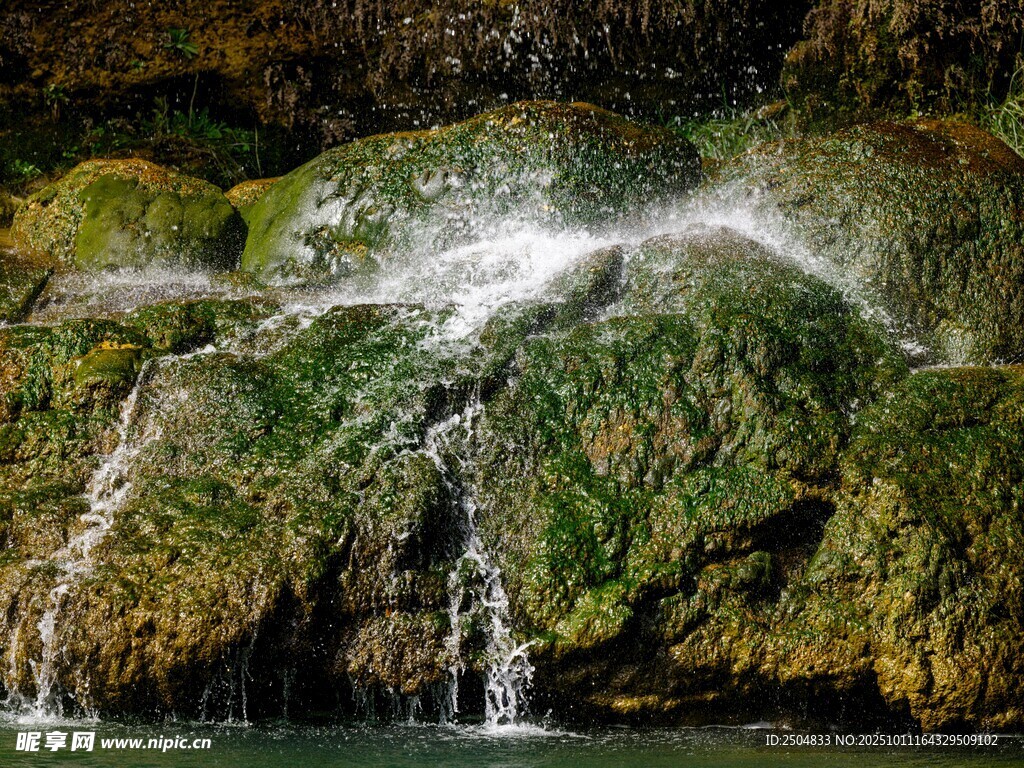 山间瀑布下的翠绿岩石