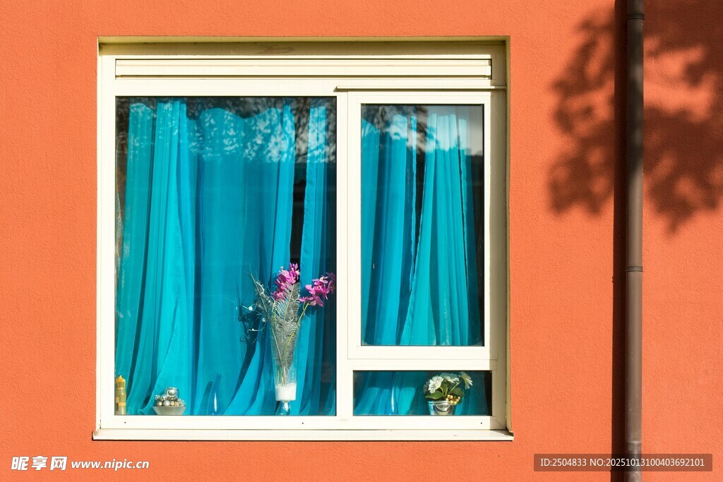 橙色墙前带蓝帘的窗户