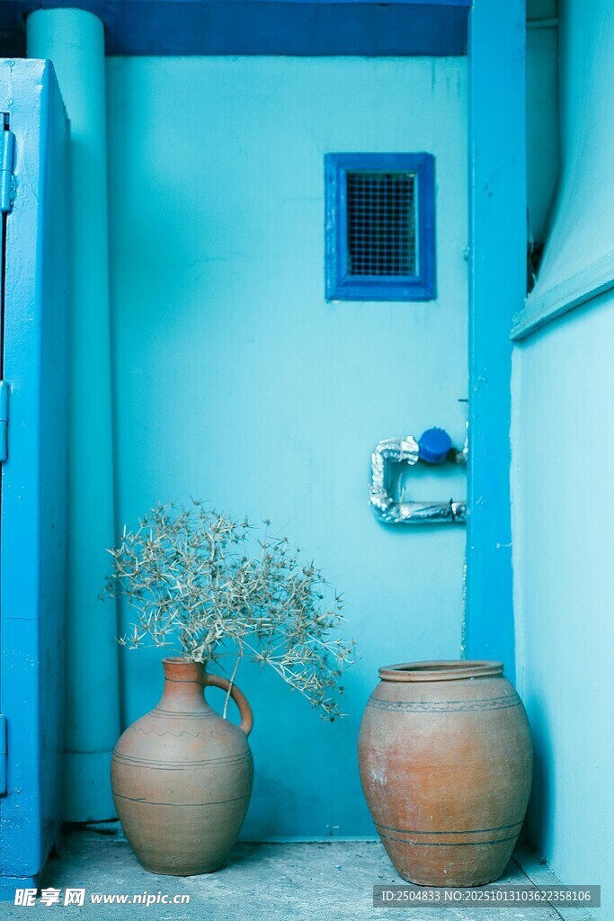 蓝墙下的古朴陶罐与绿植