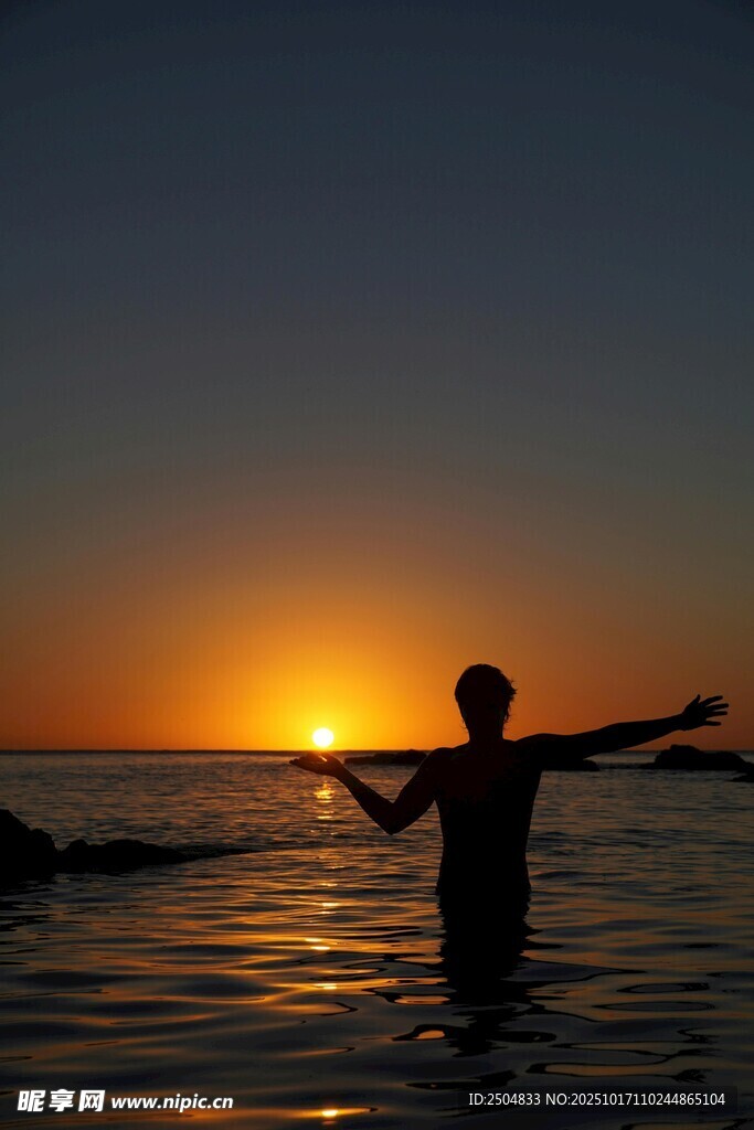 夕阳下海中伸展双臂的人