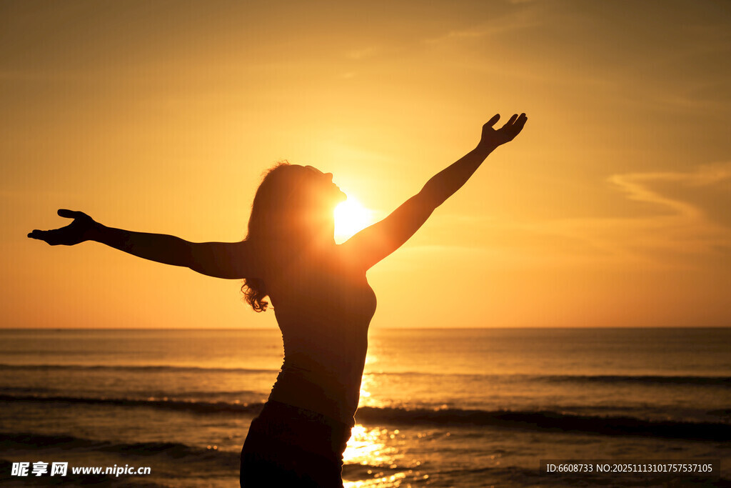 海边女子迎日落舒展双臂