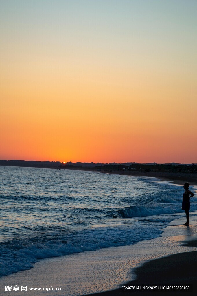夕阳下的海边漫步身影