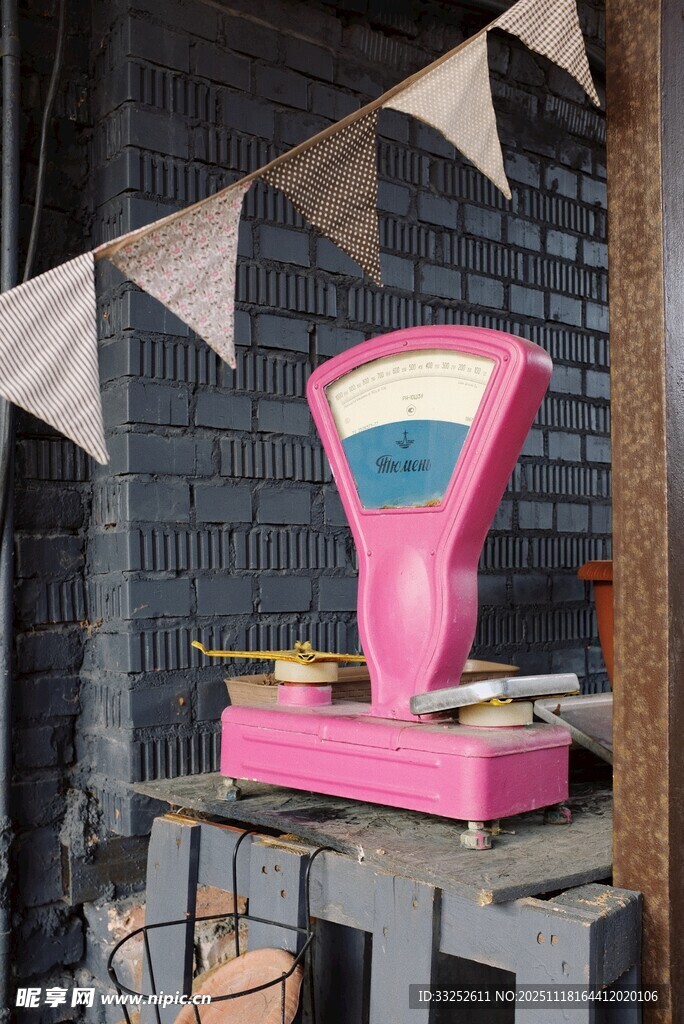 复古粉色秤置于砖墙旁