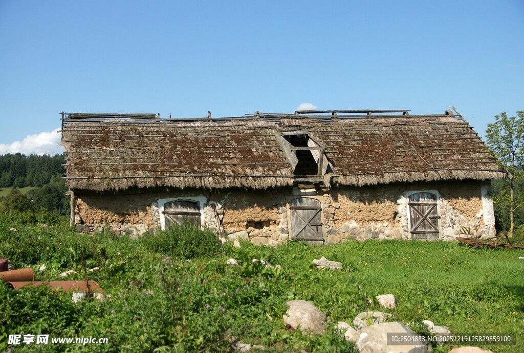 破旧石屋立于绿野蓝天间