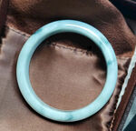 淡蓝色玉镯置于棕色布上