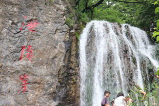 山间瀑布旁的游人赏景