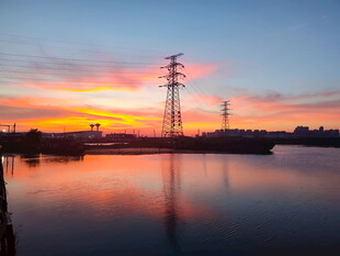 夕阳下的水边输电塔景观