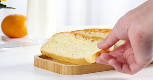 手取切片面包于木盘上