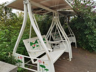 户外白色秋千椅绿植环绕