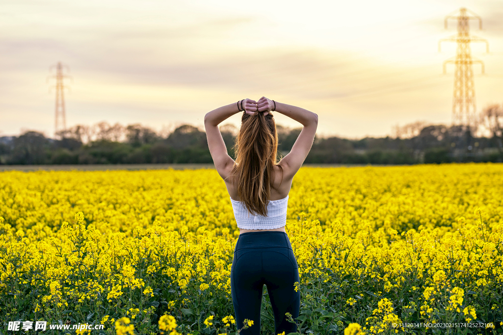 站在油菜地前的披肩发美女