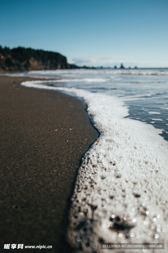 海边浪花拍打黑色沙滩