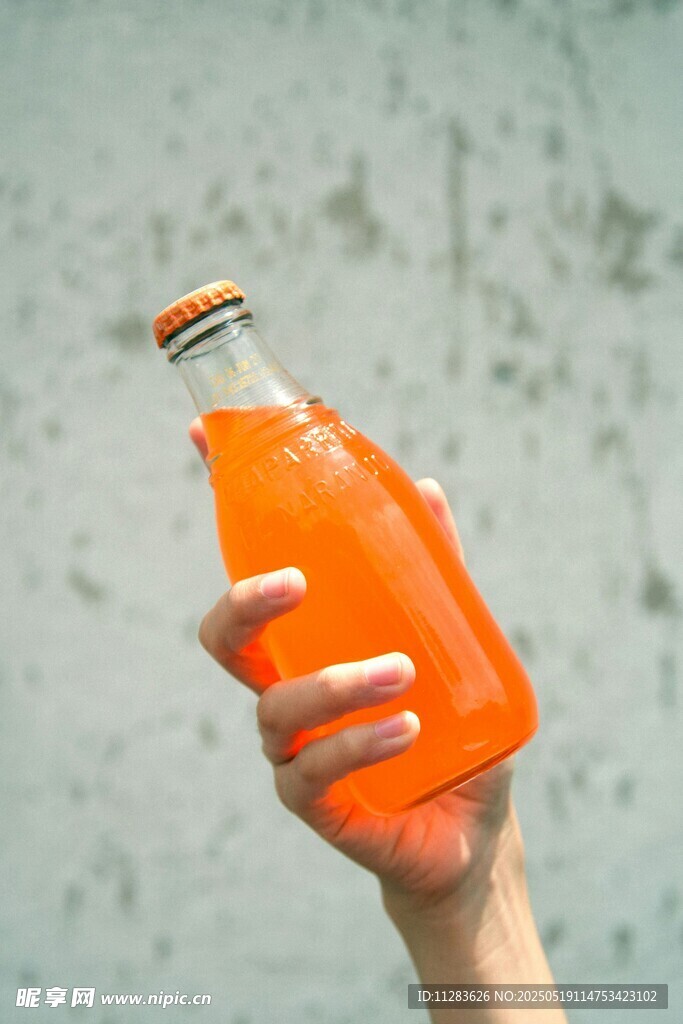 手捧橙色玻璃瓶饮料
