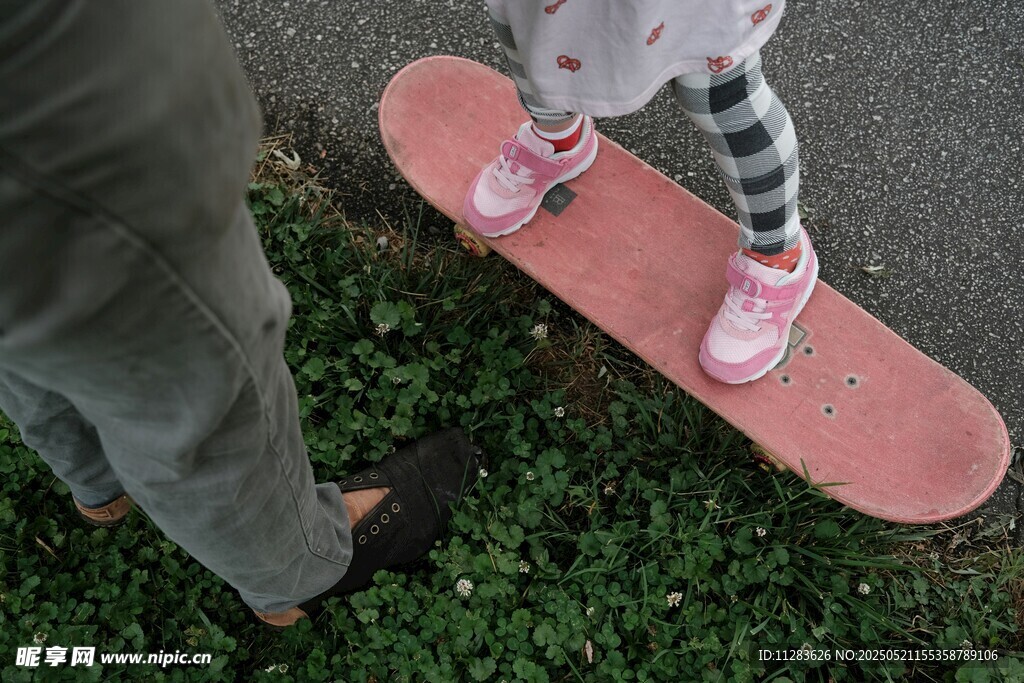 小孩在草地上玩粉色滑板