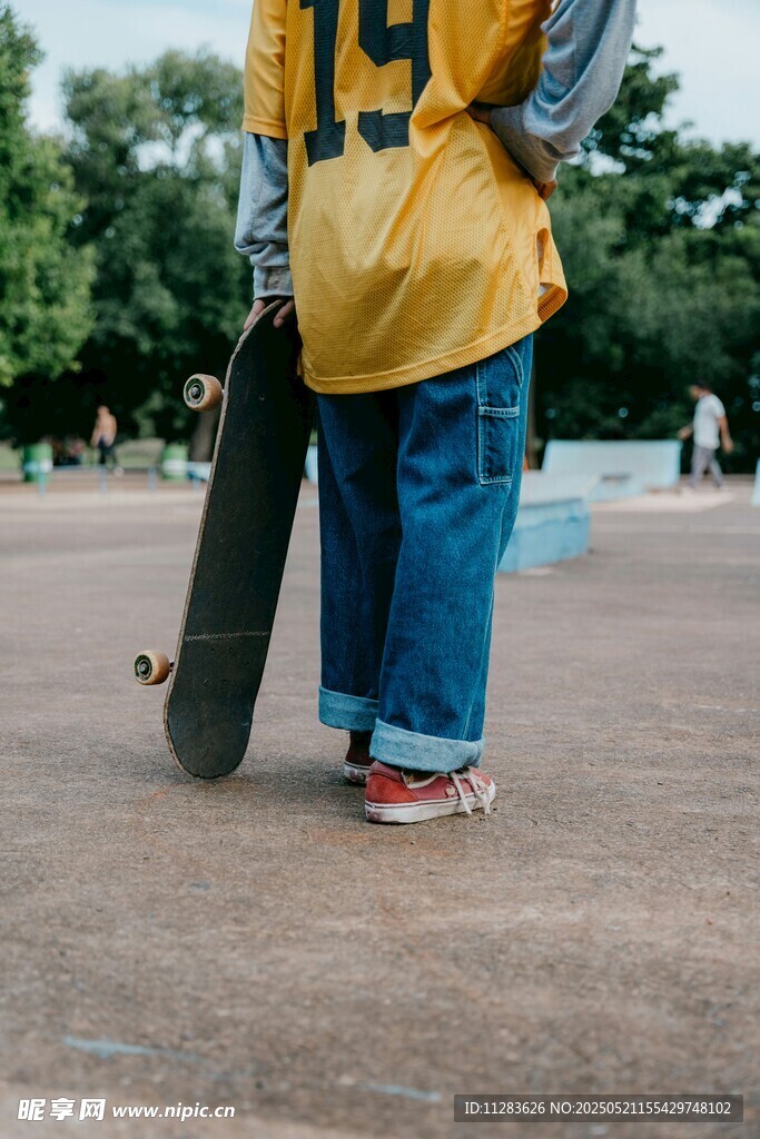 穿黄衣持滑板的少年背影