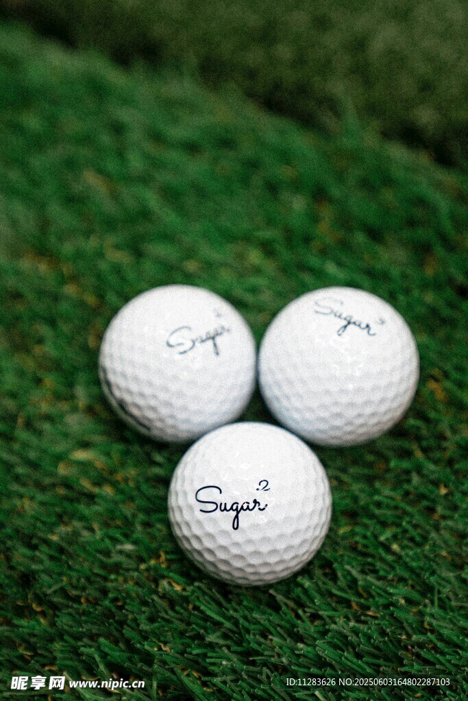 三颗高尔夫球置于绿草地上