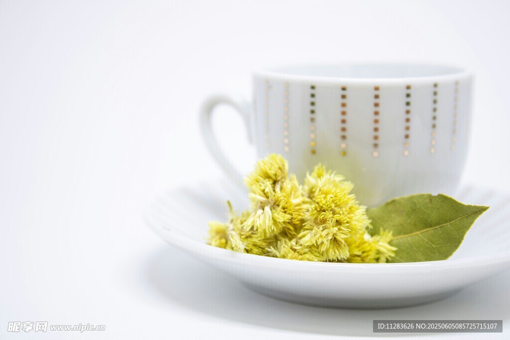 白杯旁的黄花朵与绿叶
