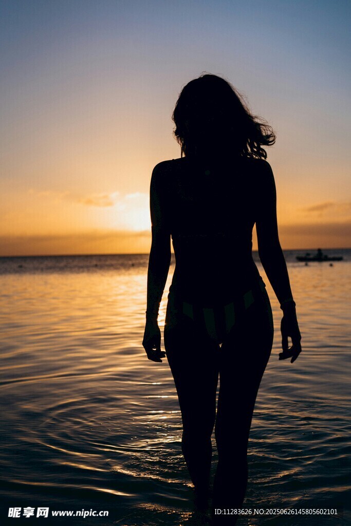 夕阳下海边漫步的女性身影