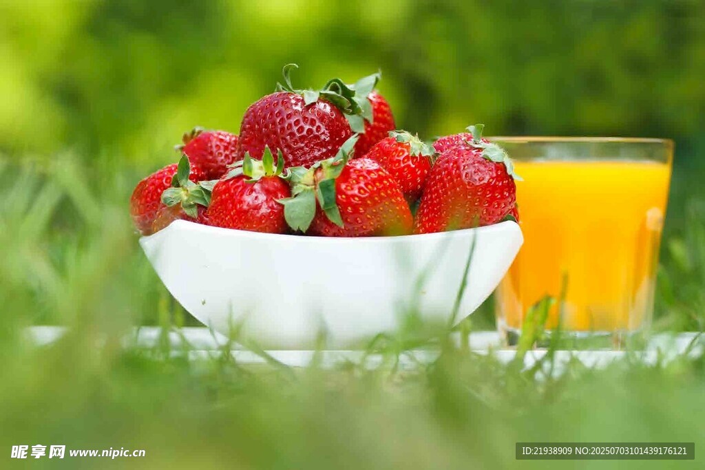 草地上的草莓与鲜榨橙汁