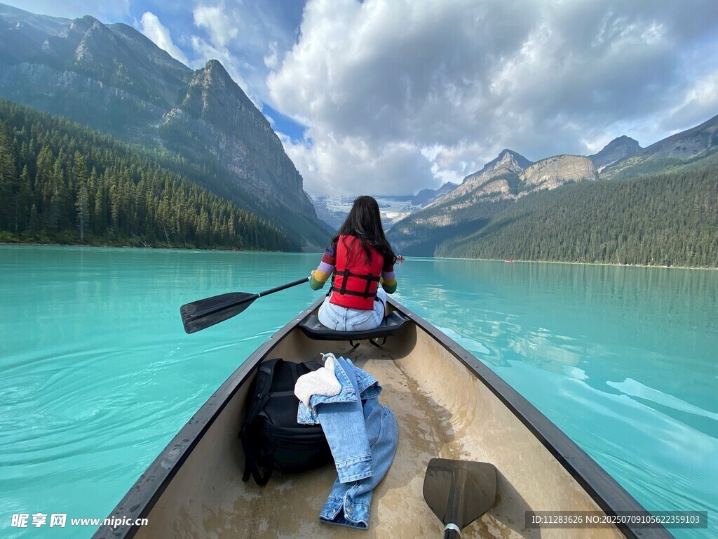 女子泛舟于碧绿湖山之间