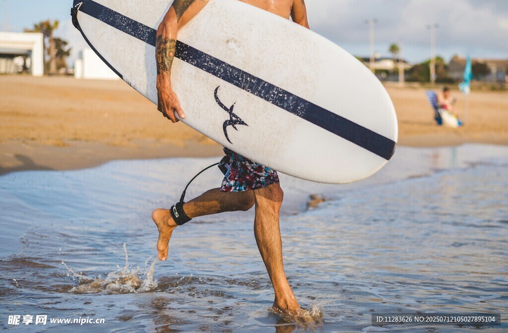 男子海边扛冲浪板踏浪