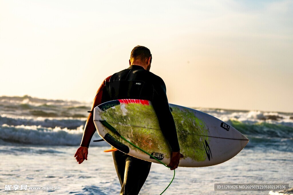 冲浪者持板漫步海滩