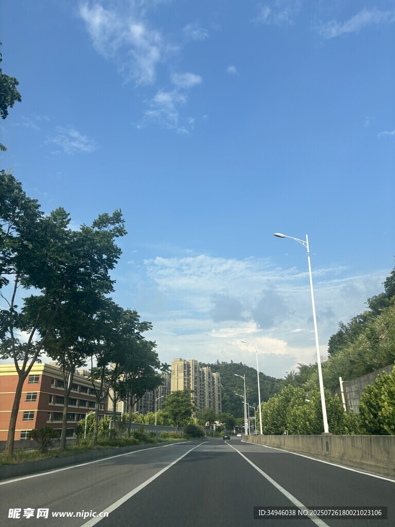 宽阔公路旁绿树蓝天相伴