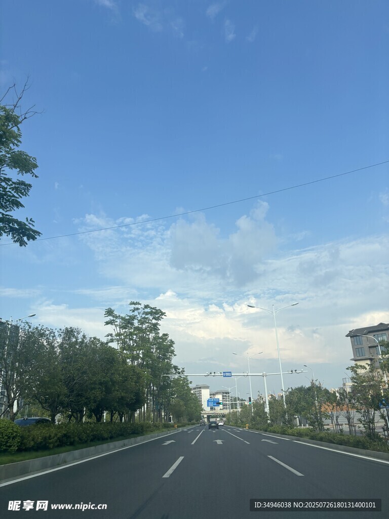 宽阔公路旁绿树蓝天白云