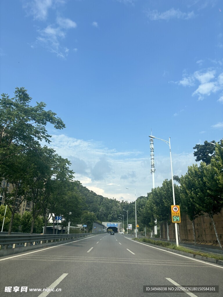 宽阔公路旁绿树蓝天白云