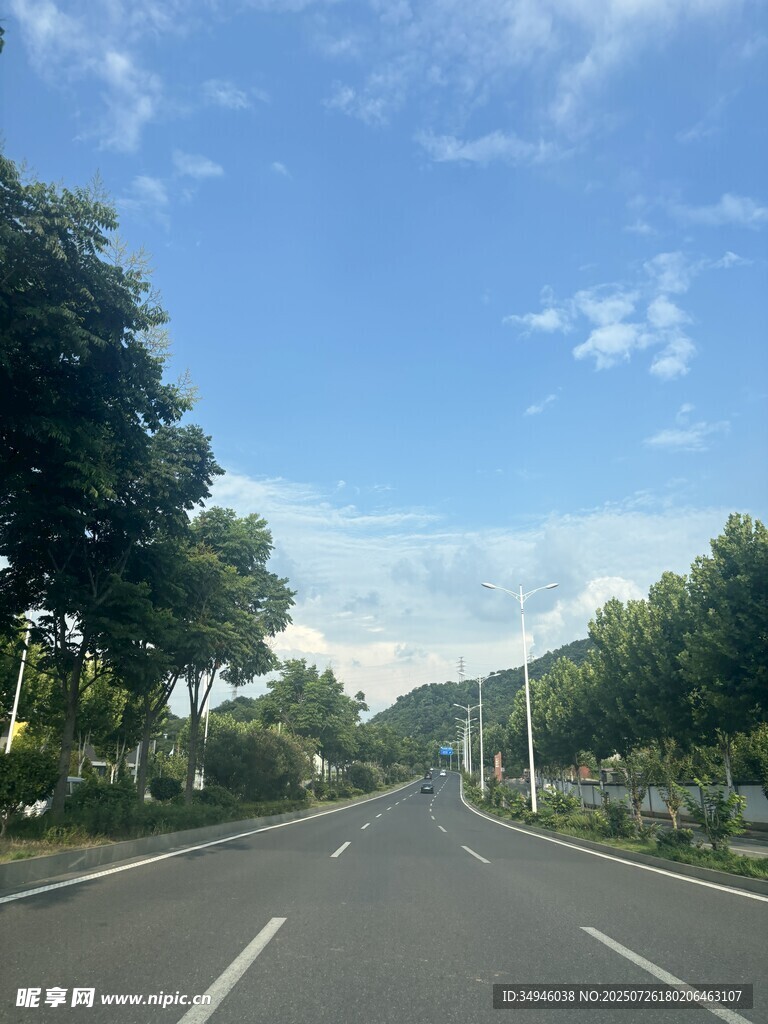 宽阔公路旁绿树蓝天白云