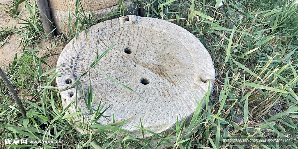 古老石磨盘置于草地