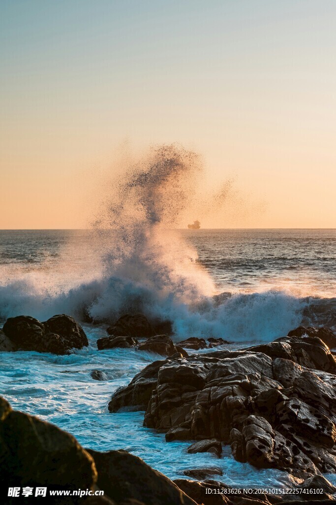 夕阳下海浪拍打礁石美景