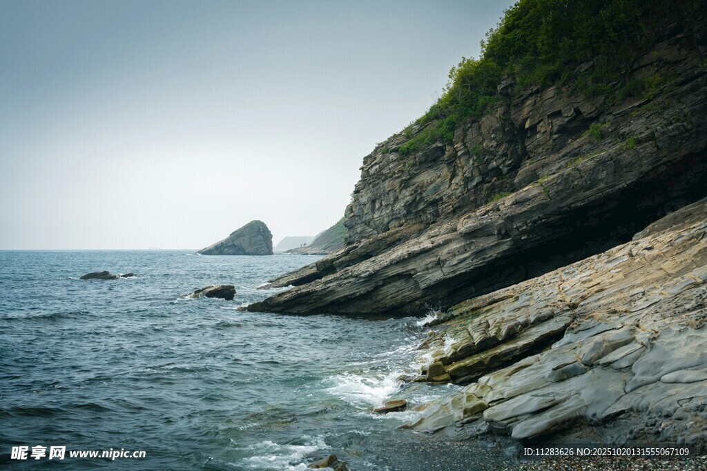 海边嶙峋岩石与远处孤峰