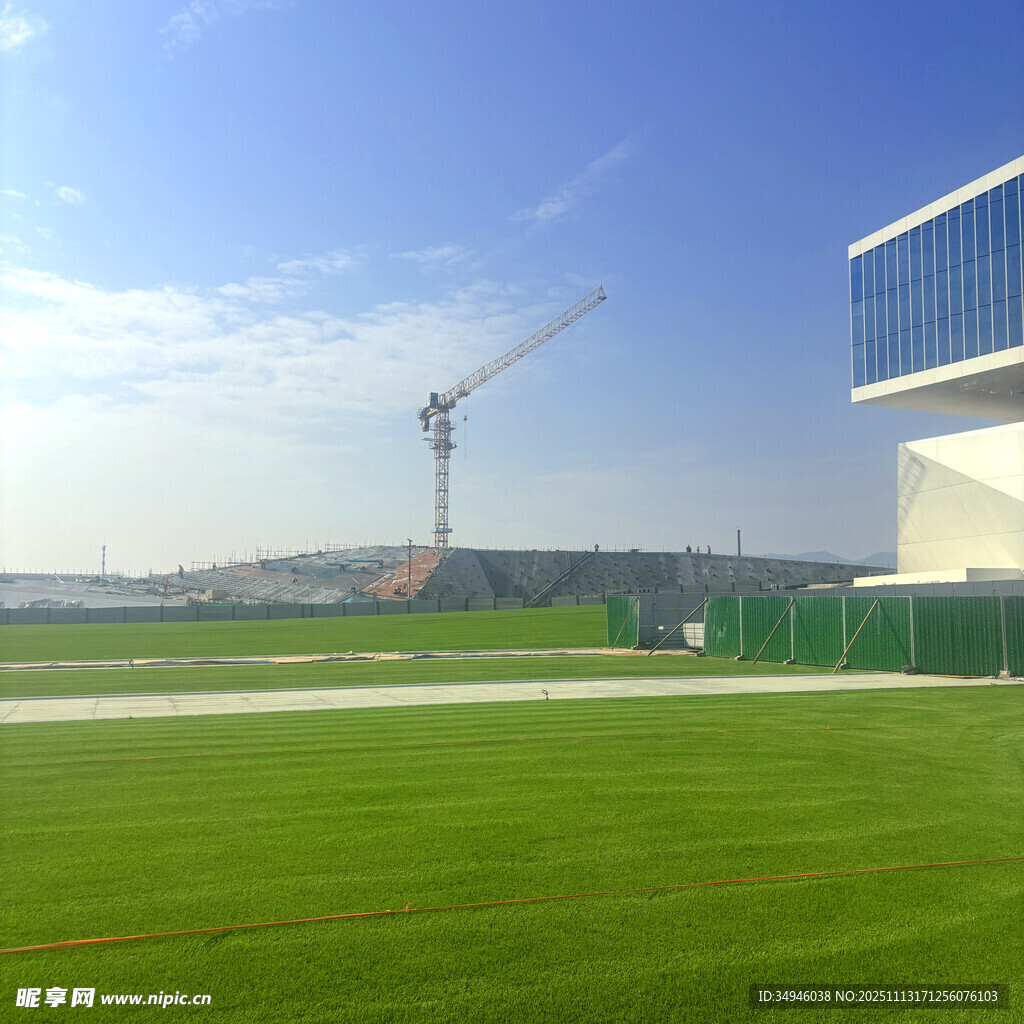 户外绿茵场与远处建筑塔吊