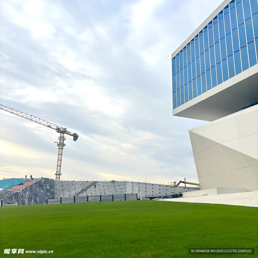 现代建筑旁的绿地与起重机