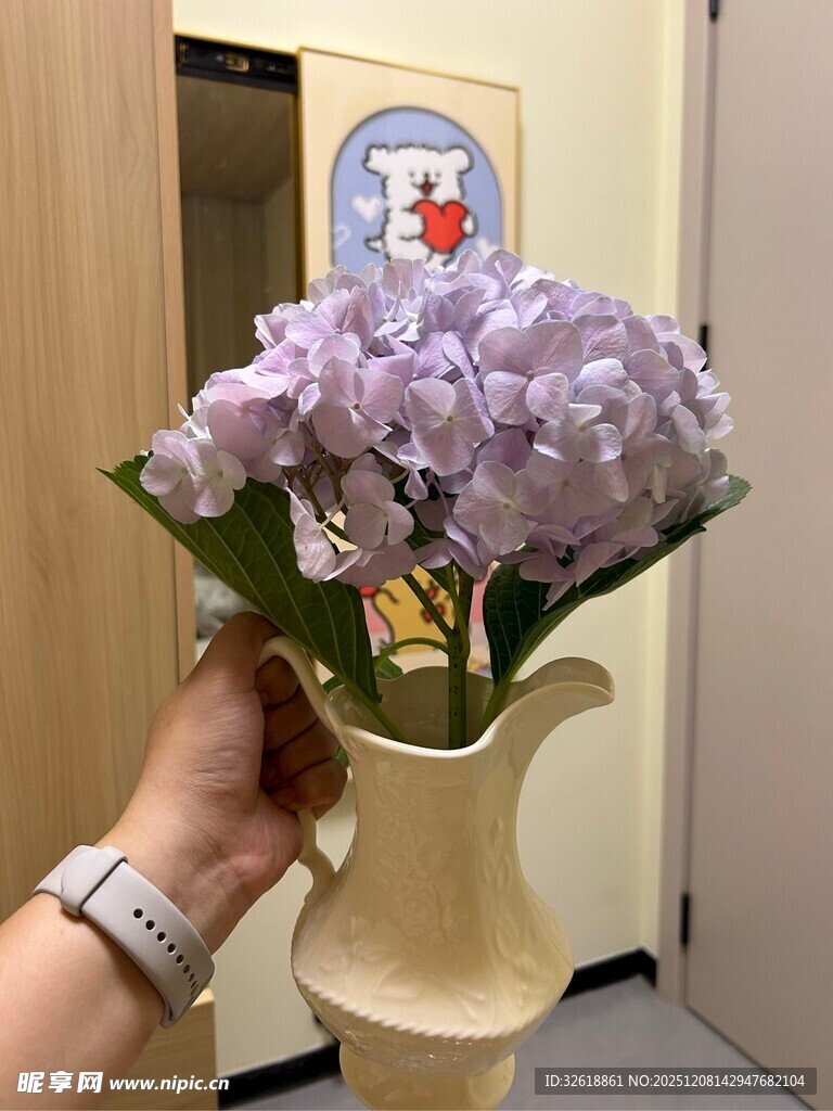 手捧紫花插于米色花瓶
