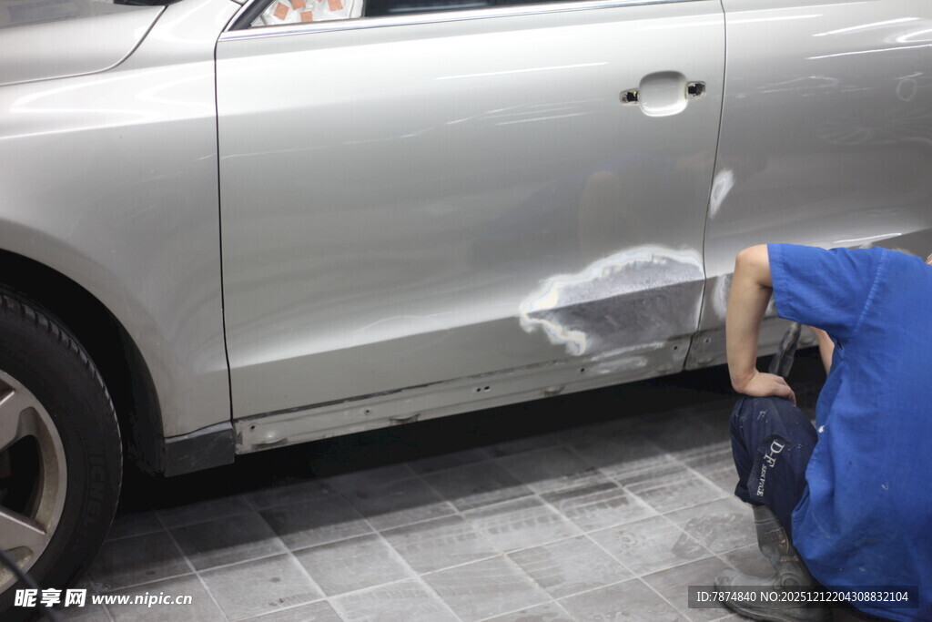 工人专注修复汽车凹陷处