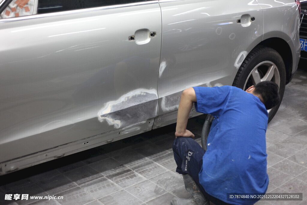 工人专注修补银色汽车