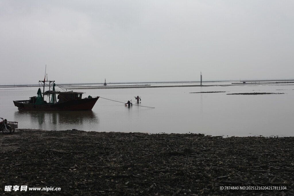 海边停泊的渔船与涉水者