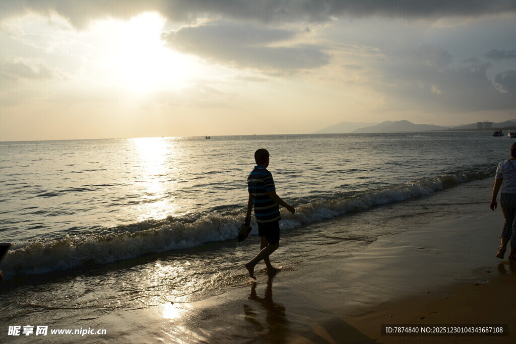 夕阳下的海边漫步身影