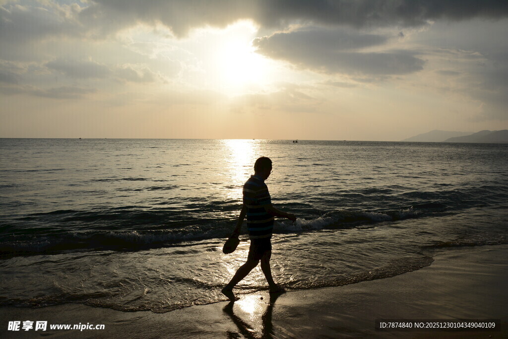 夕阳下海边独自行走的人