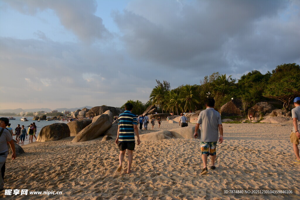 黄昏下的沙滩漫步人群